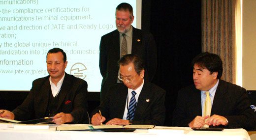 写真1:調印式の模様。左からIPv6 Forum議長のLatif Ladid氏、JATE理事長の須田 和博氏、IPv6 Ready Logo Committee議長の江崎 浩 東京大学大学院教授。後方はオーストラリアISOC代表Tony Hill氏(写真撮影:インプレスR&Dコントリビューティング・エディタ 松原由高)